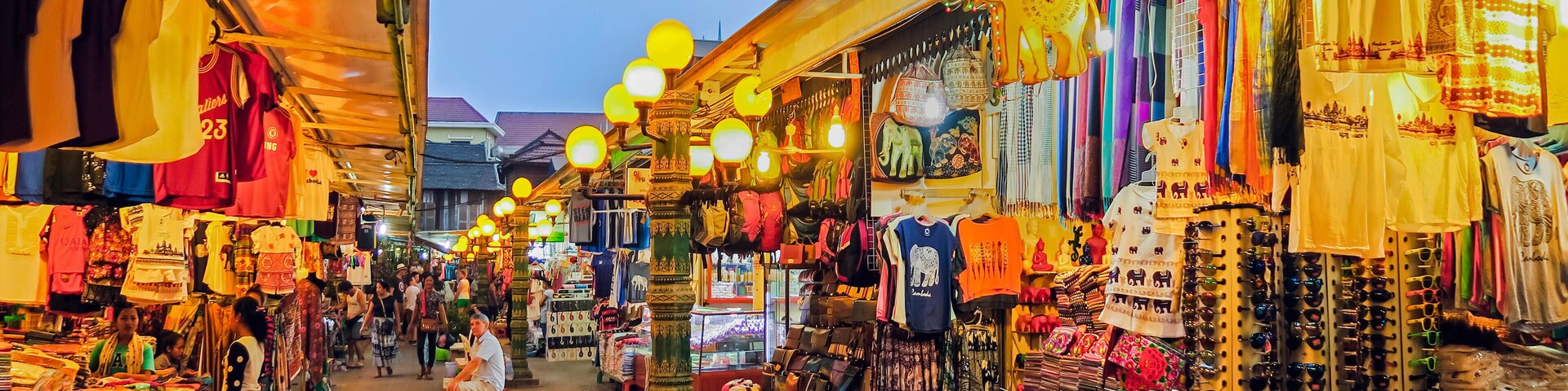 A bustling market with various stalls selling clothes, bags, and accessories.