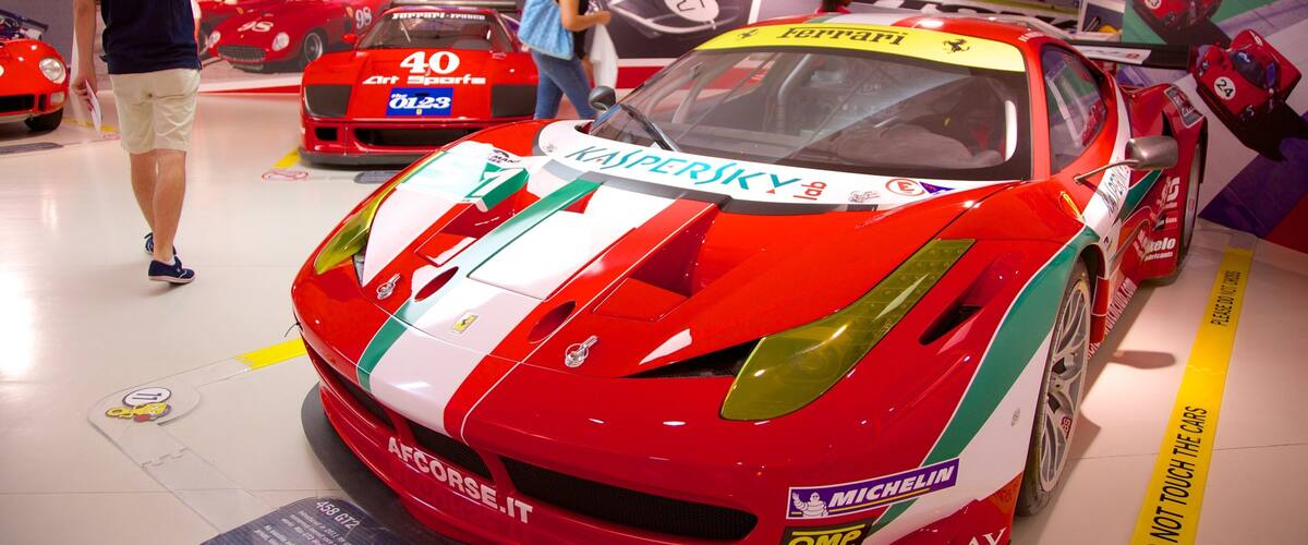 A red and white sports car with 'Ferrari' and 'Kaspersky' logos, displayed at a car show.