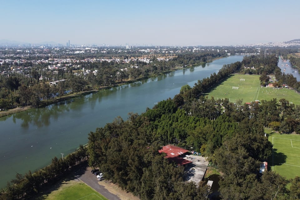 A river winding through a city, surrounded by dense forests and a soccer field.
