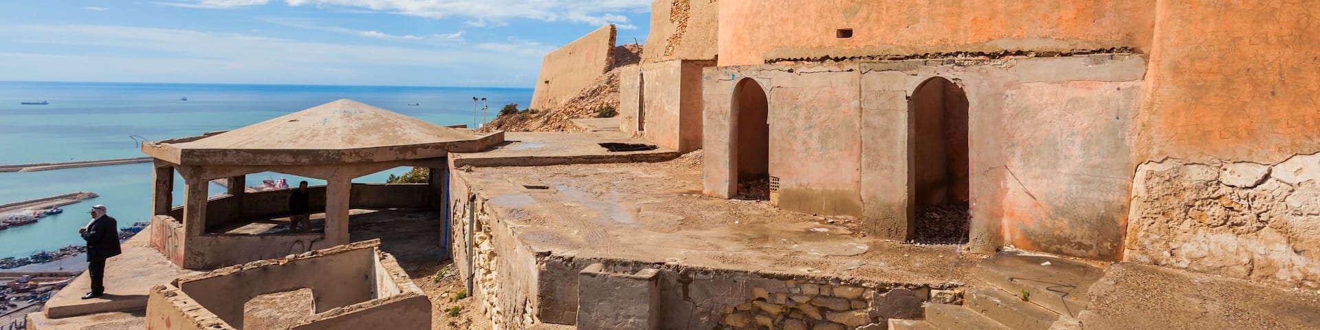 A coastal fortification with arched doorways and a watchtower overlooking the sea.