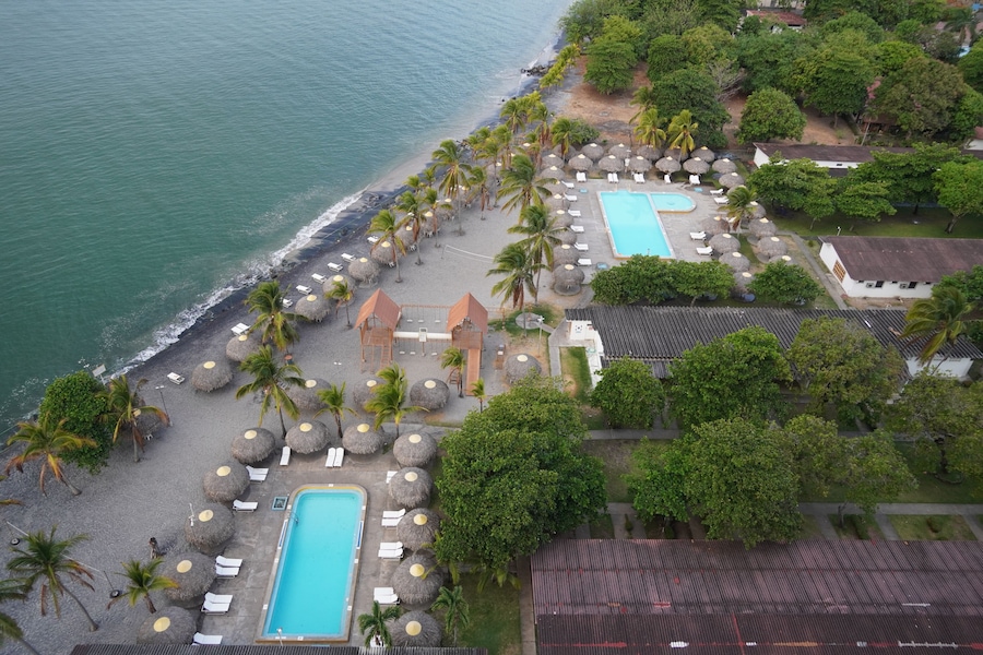 Un resort con piscina, playa, palmeras y vista al océano.