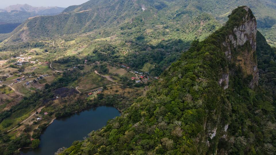 A mountainous landscape with a lake, a village, and a prominent cliff.