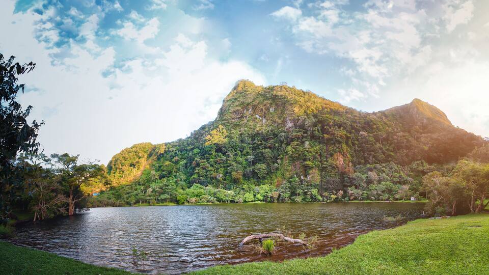 A lake surrounded by lush greenery and a mountain.