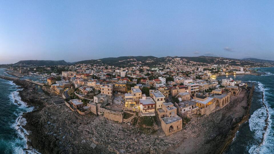 Panoramic sunset view of Batroun, Lebanon, showcasing the coastal city's blend of ancient walls, modern buildings, and picturesque shoreline along the Mediterranean Sea