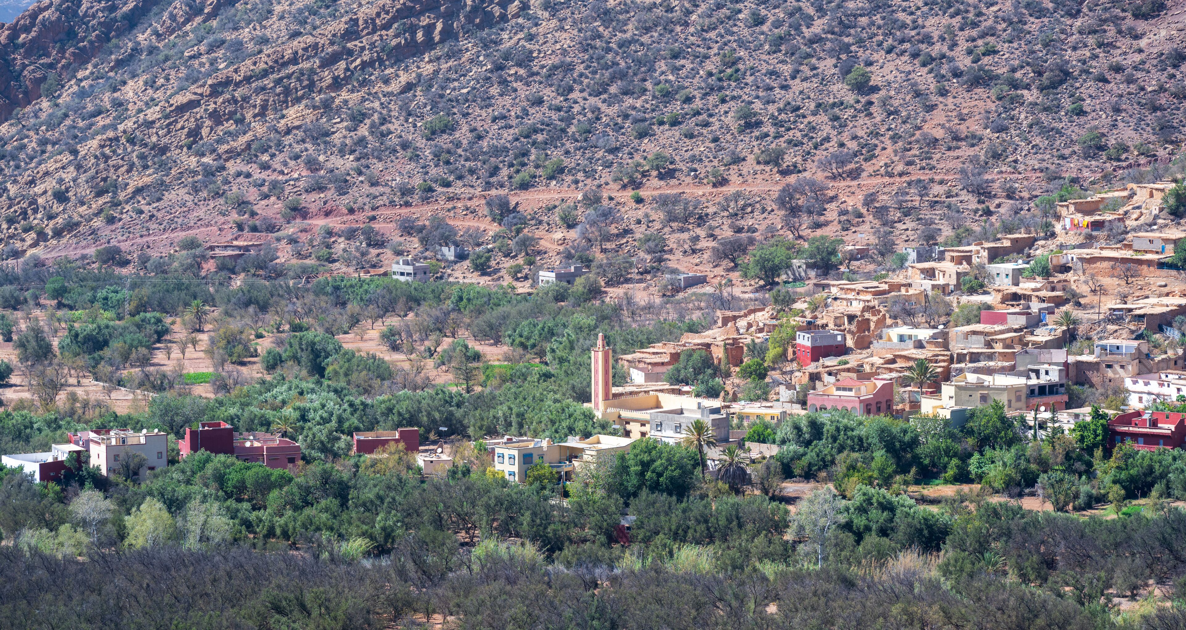 A mountainous village with traditional buildings and a prominent minaret.