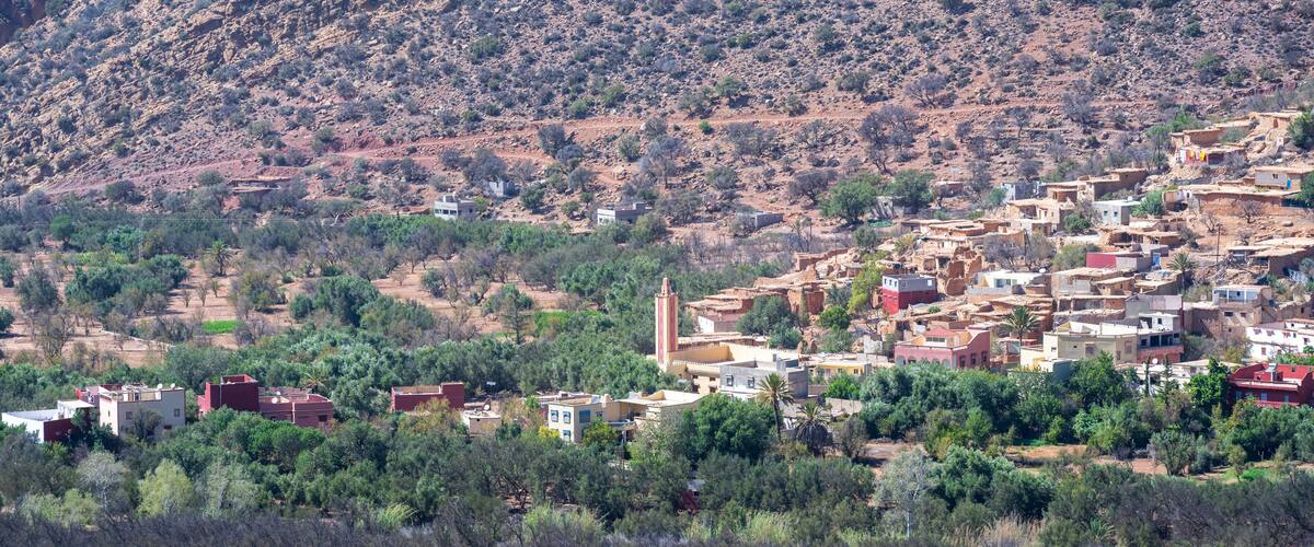 A mountainous village with traditional buildings and a prominent minaret.