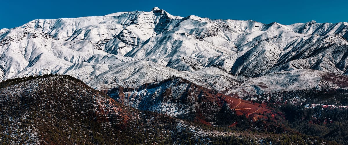 A snow-covered mountain range with a clear blue sky.