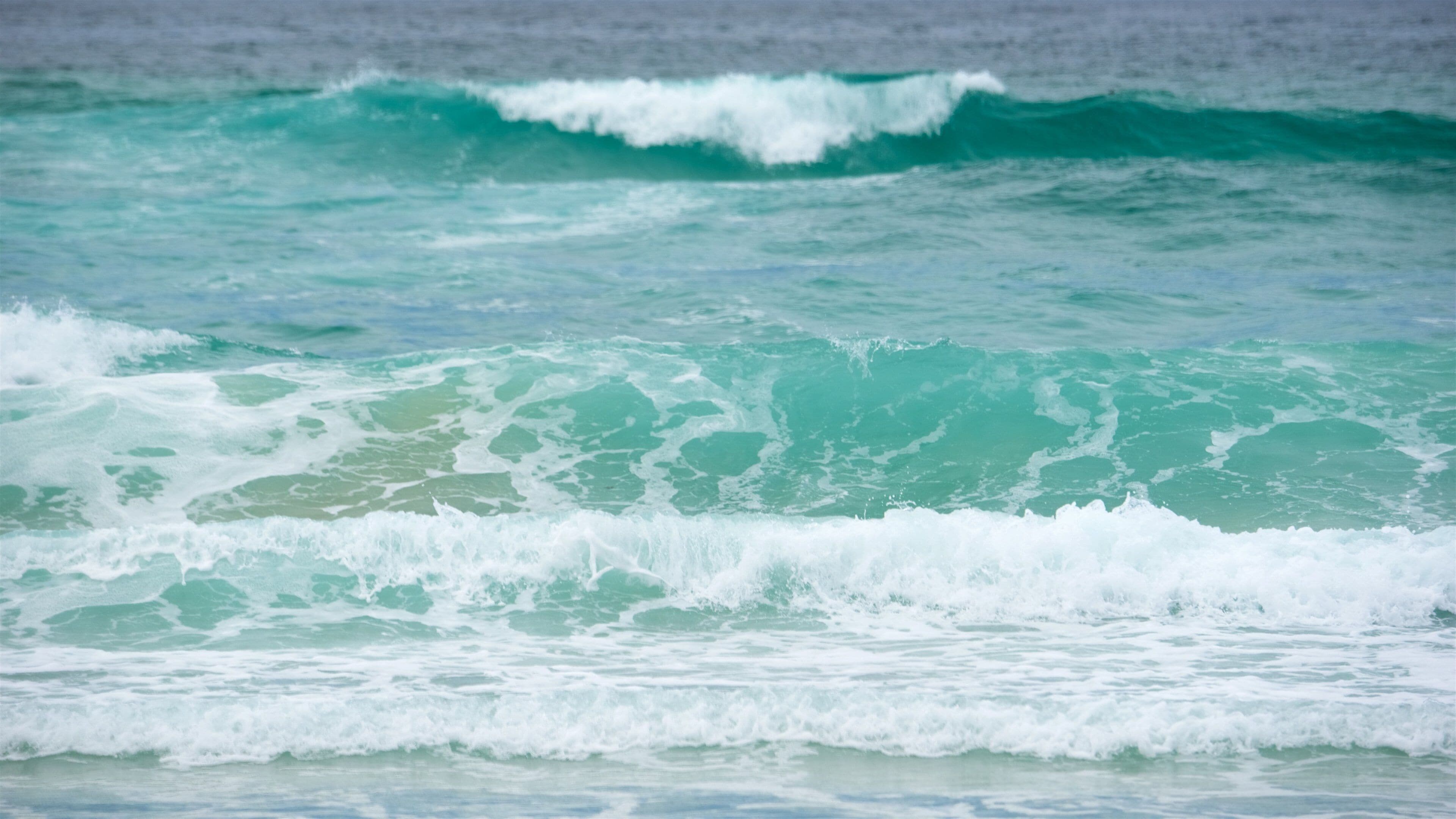 Turquoise ocean waves with white foam.