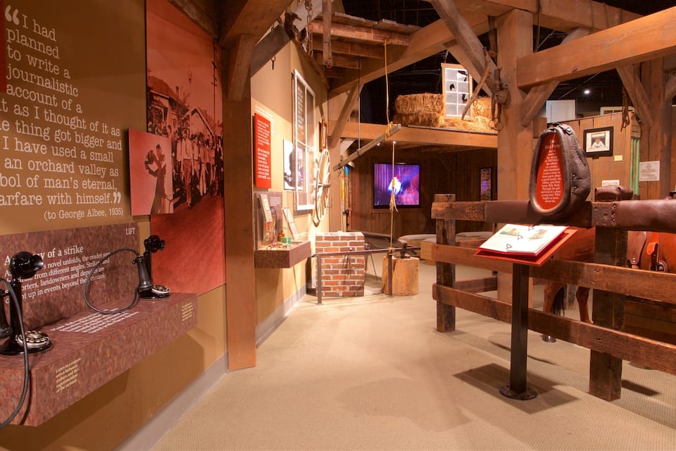 An exhibition with historical artifacts, including a vintage telephone, a wooden wagon, and a horse.