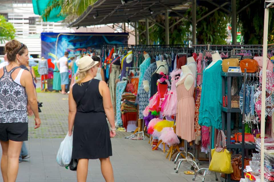 Un marché animé en plein air, avec de nombreux étals proposant des vêtements et des accessoires.