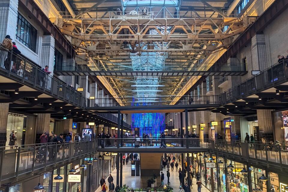 A multi-level shopping mall with a prominent ceiling structure and various retail stores.
