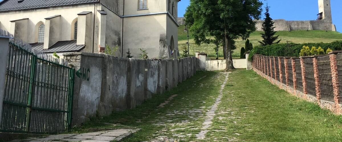 A church with a bell tower, a cobblestone path, and a castle in the background.