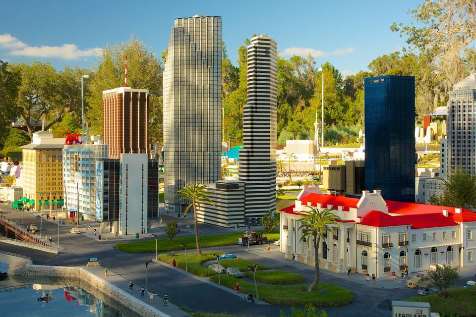 Un modelo detallado de un paisaje urbano con varios edificios, incluyendo un rascacielos alto, un edificio moderno y un edificio histórico con tejado rojo.