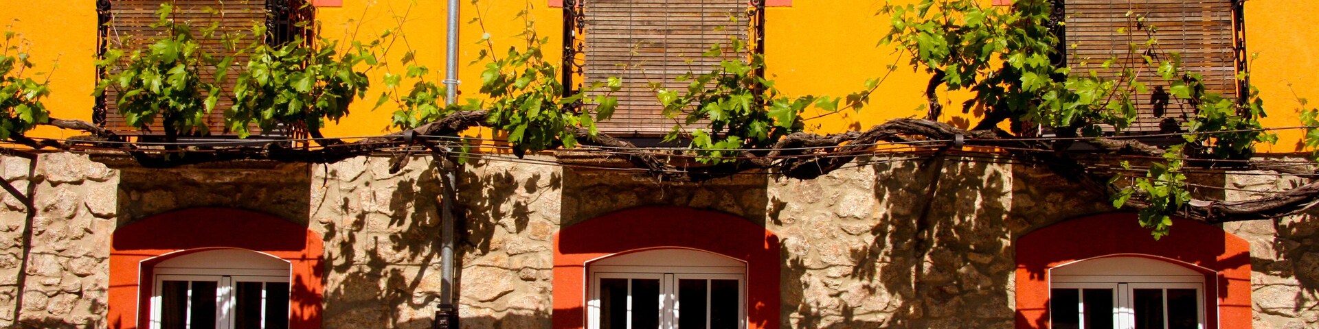 Un edificio con tres ventanas de arco y fachada de piedra.