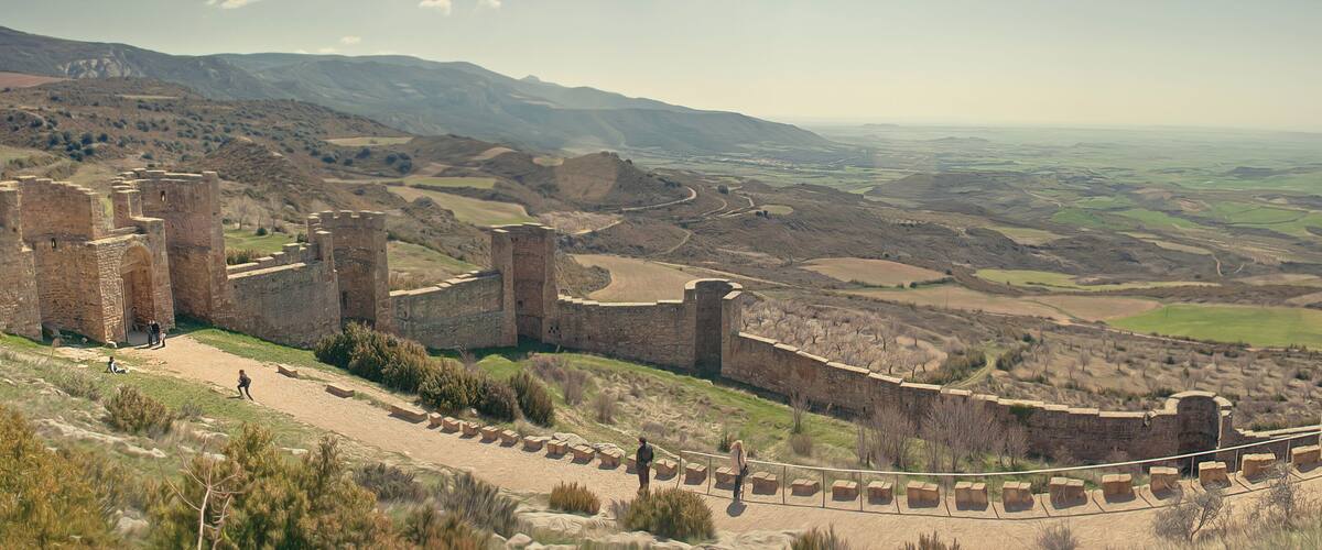 A historic castle with a surrounding moat and a scenic view of rolling hills and valleys.