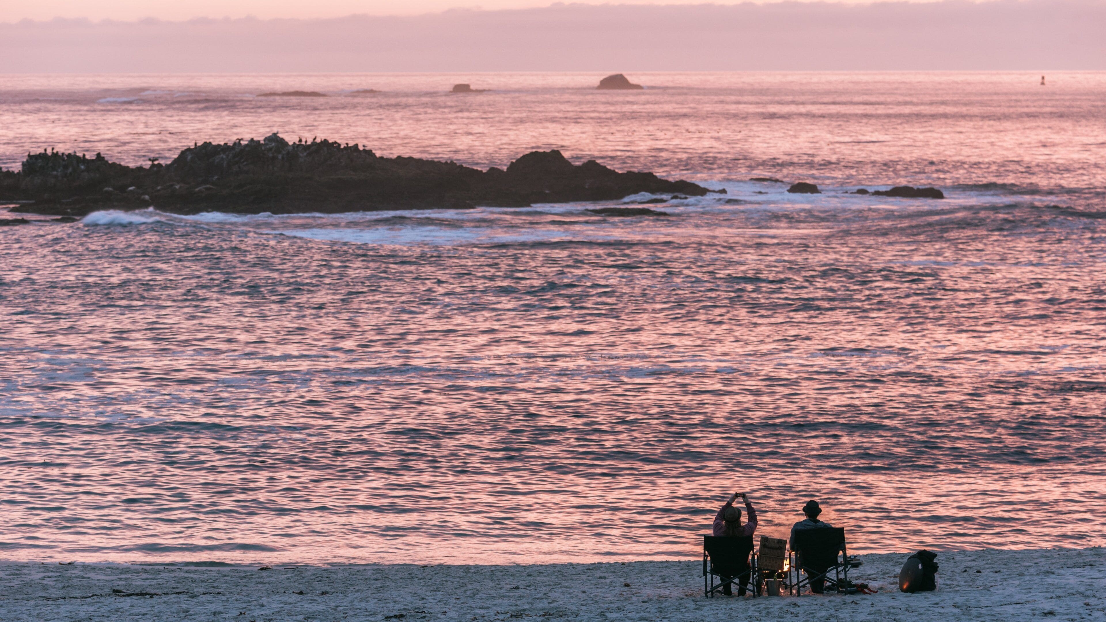 17-Mile Drive mostrando una playa y un atardecer y también una pareja