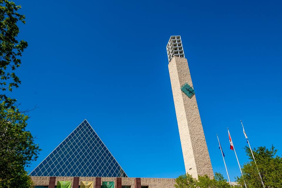 Une haute tour surmontée d’une horloge et d’une structure en forme de pyramide.