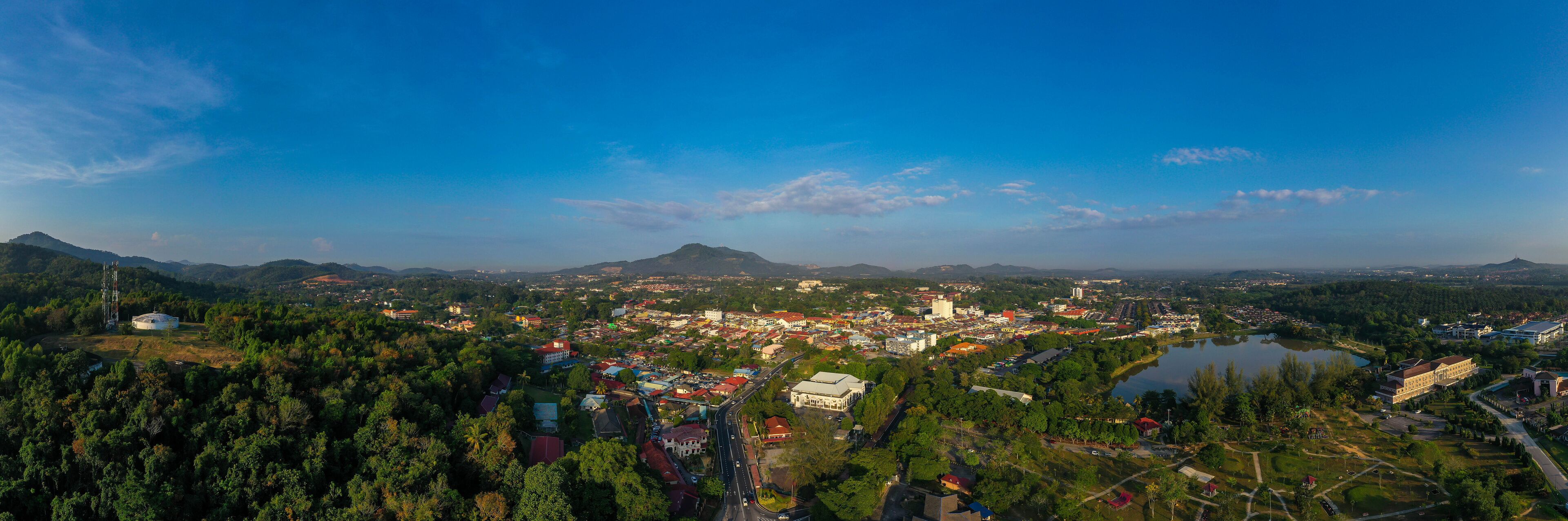 A town with a river, surrounded by mountains and dense forests.