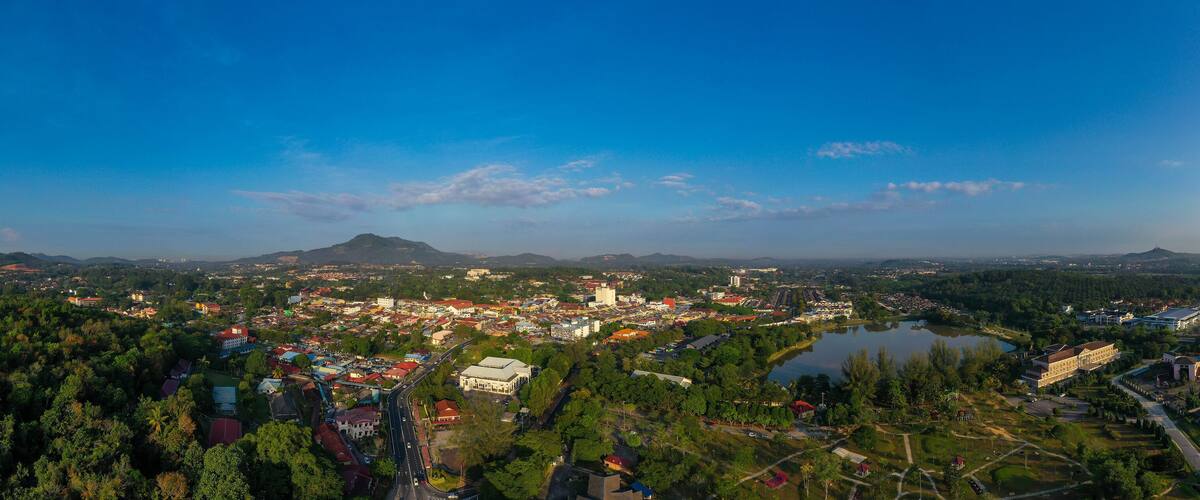 A town with a river, surrounded by mountains and dense forests.