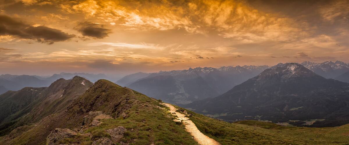 A mountain landscape with a dirt path leading to a peak.