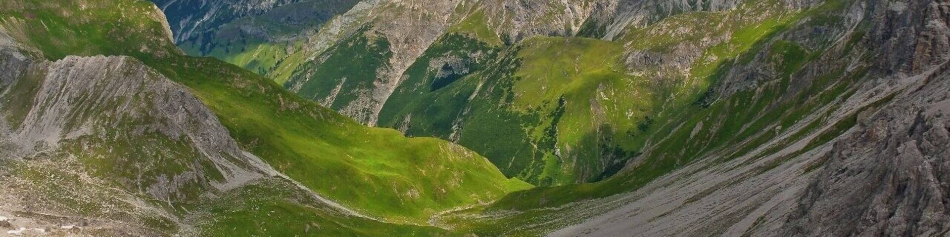 July 2015
Lechtaler Alps, Tyrolia, Austria
View from Grossberg Kopf (alt. 2.612 m) towards
Roettal valley over Madau village. In the middle are the passes
Am Nocken (2.032 m) and
Streichgampenjoechl (2.221 m). The summits are
Hengstspitzen (2.539 to 2.599 m) and
Landschaftseck ( 2.610 m). You will go through this valley when trekking from
Memminger Huette to Gramais or Madau.
It is a typical scenery of Lechtaler Alps with lush green meadows and light grey limestone ranges over them.