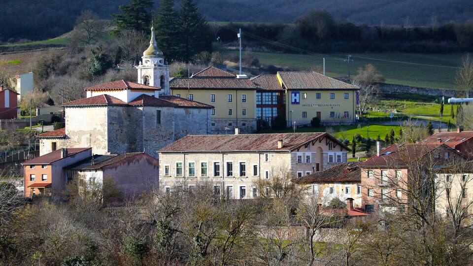 A historic town with a prominent church, a hotel, and surrounding greenery.