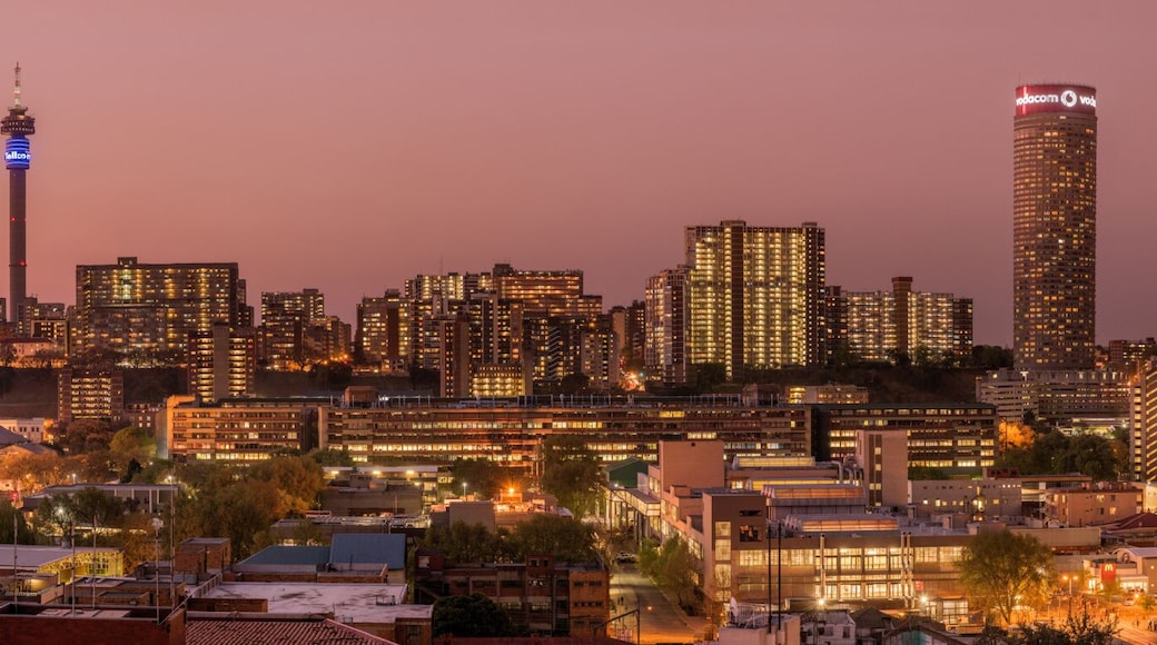 A beautiful and dramatic panoramic photograph of the Johannesburg city skyline, taken on a golden evening after sunset.