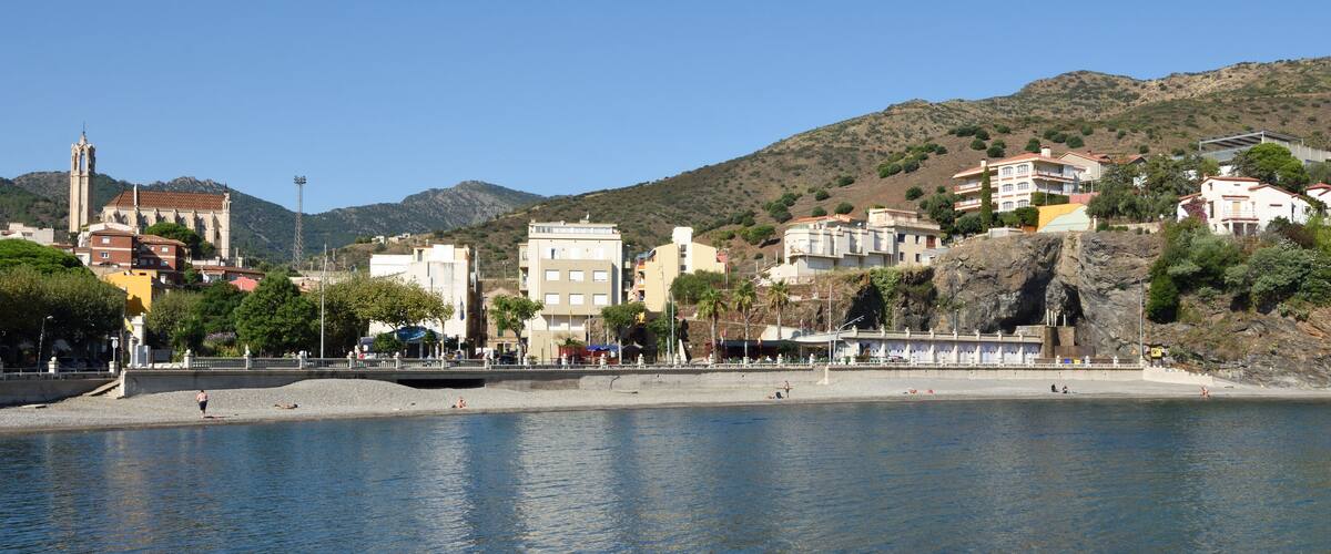 A coastal town with a prominent church, buildings, and a rocky shoreline.