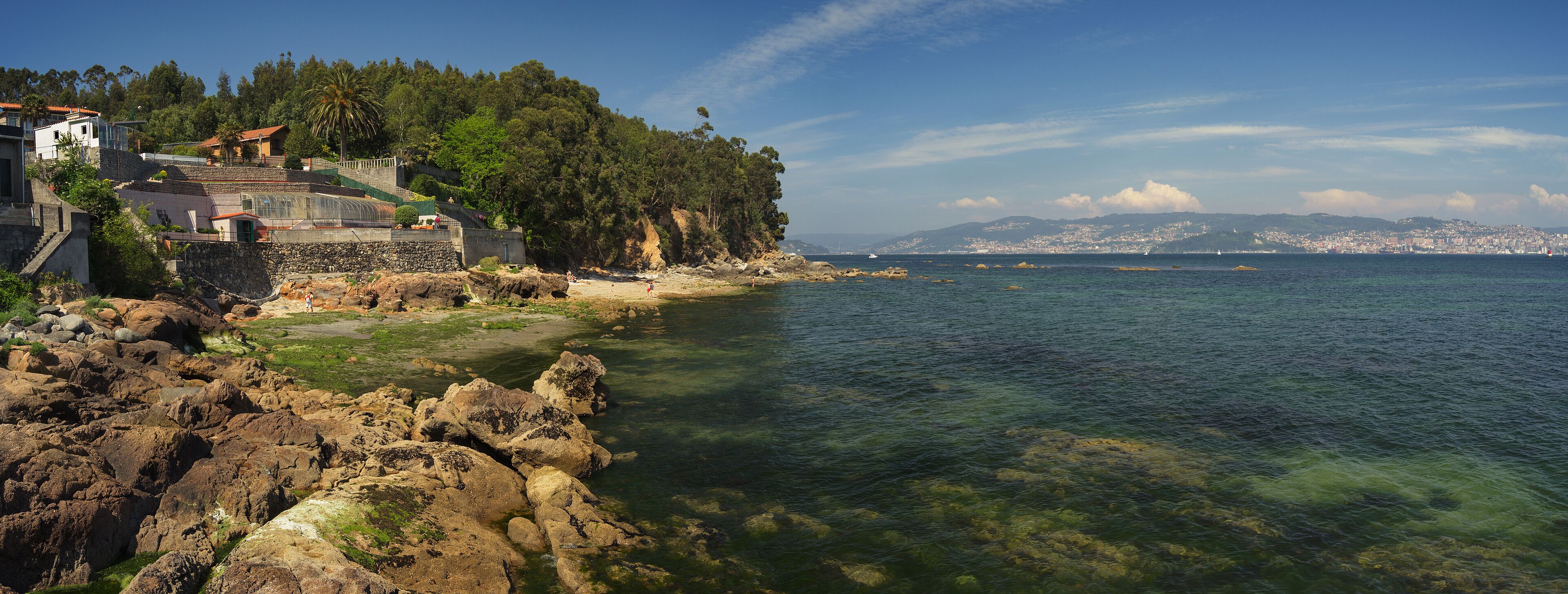 Panoramic of a small beach between Cangas and Moaña. Transparent green water with Vigo City in the background