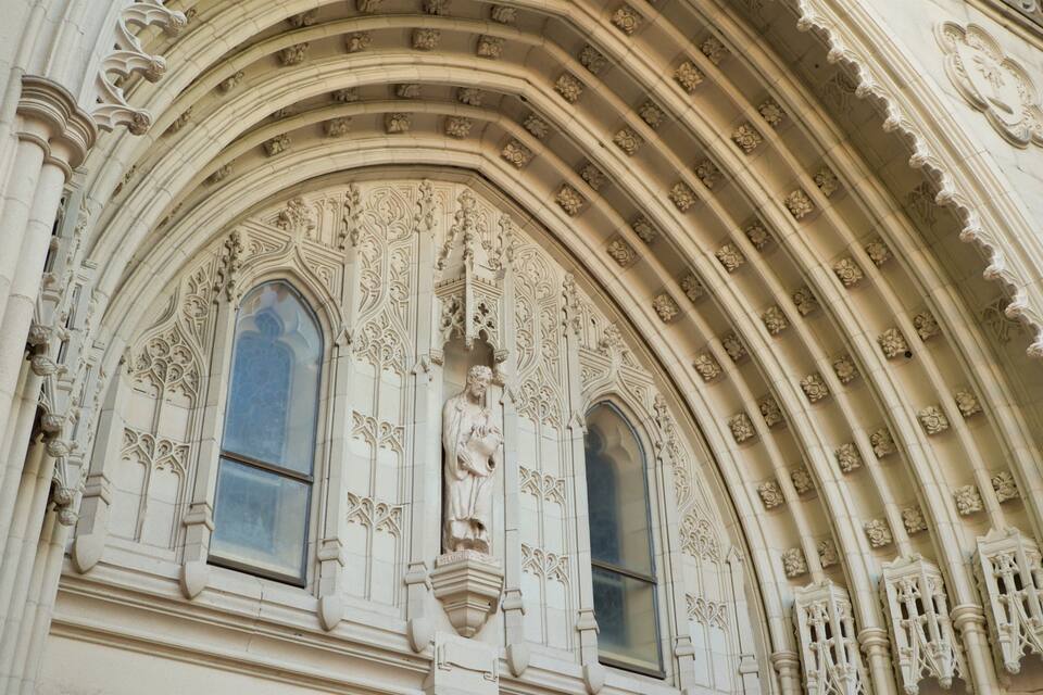 A Gothic-style window with intricate tracery and a statue of a saint.