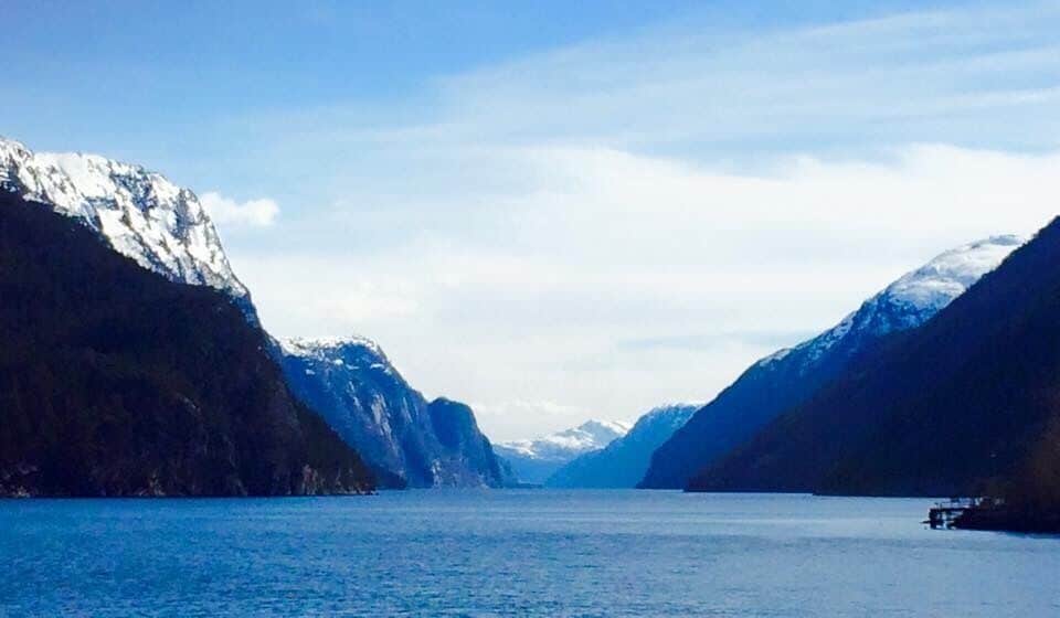 Un fiordo con montañas nevadas a ambos lados y aguas tranquilas.