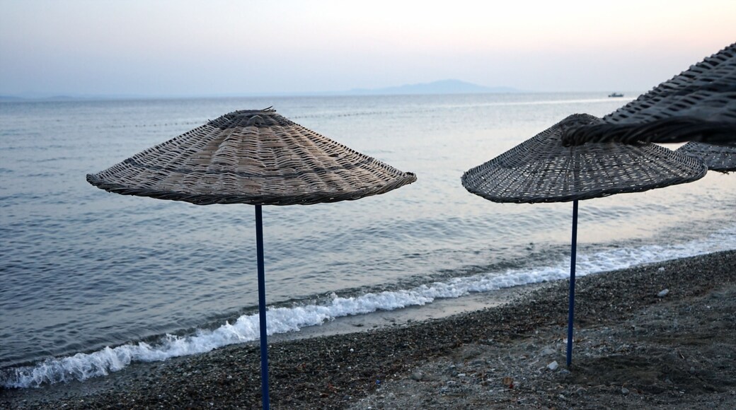 Blick vom Strand in Altinoluk mit Sonnenschirm aus Korbgeflecht im romantischen Licht der untergehenden Sonne auf den Golf von Edremit am Ägäischen Meer in der Provinz Balikesir in der Türkei
