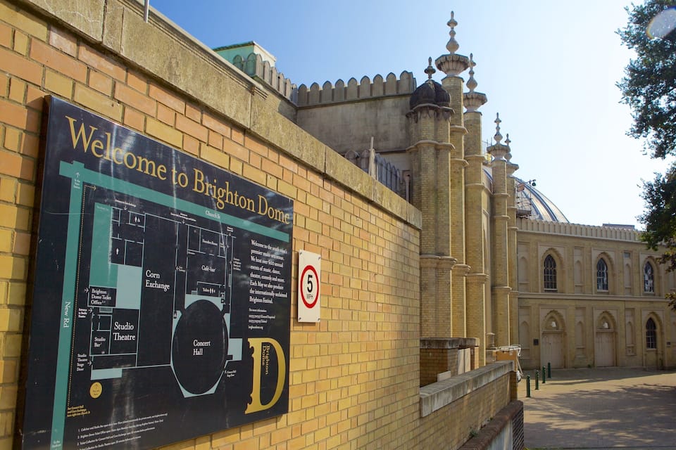Un cartello di benvenuto ai visitatori del Brighton Dome, un edificio storico caratterizzato da una cupola e finestre ad arco.