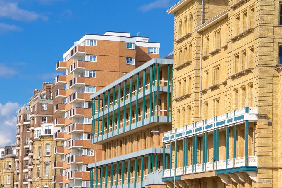 A row of modern and historic buildings with balconies and large windows.