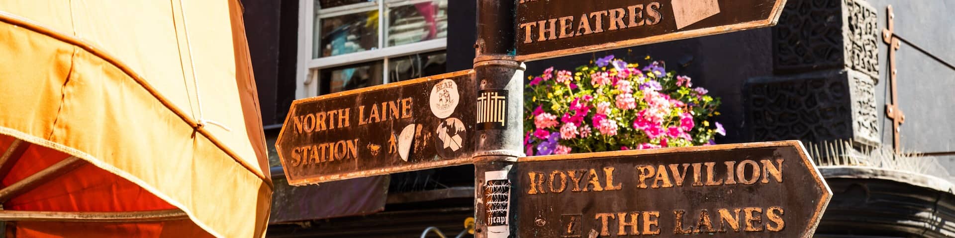 A directional signpost with multiple arrows pointing to various attractions including North Laine Station, Museum Library Theatres, Royal Pavilion, and The Lanes.