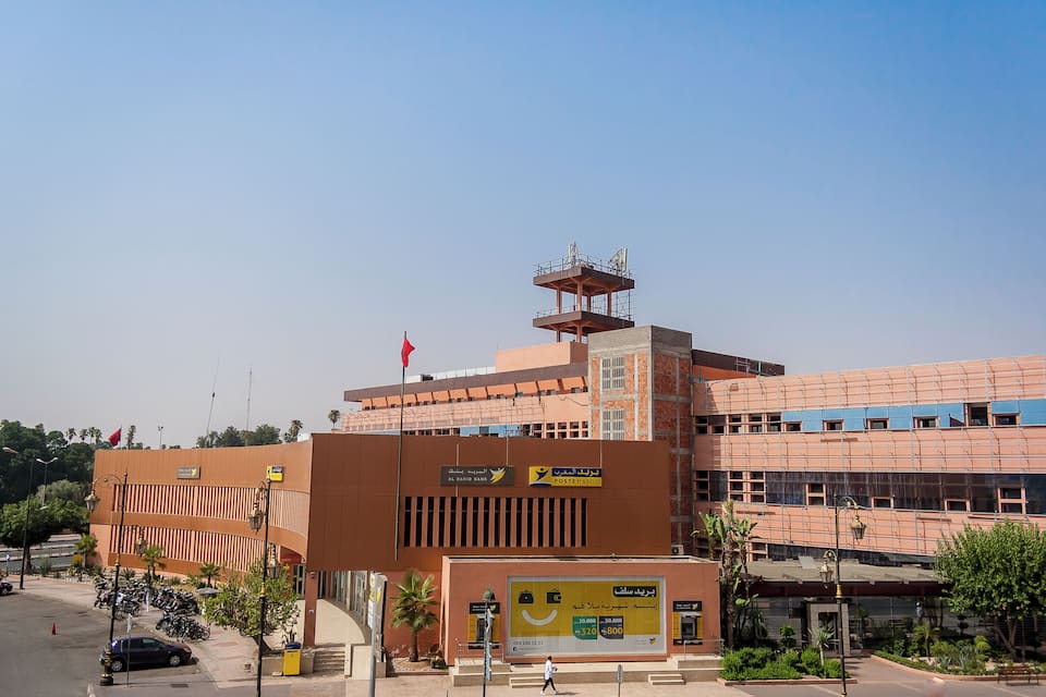 A large building with a red flag, a billboard, and parked motorcycles.