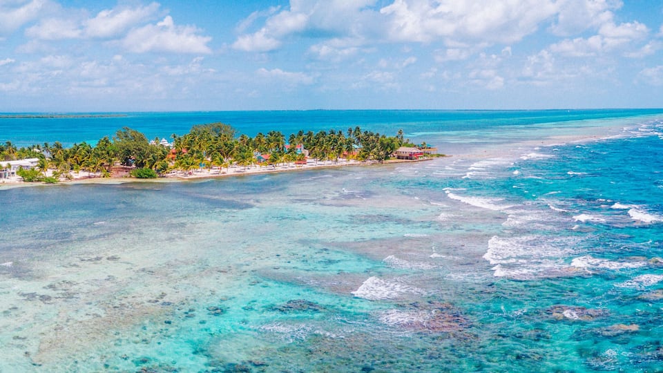 A tropical island with clear turquoise waters, a sandy beach, and lush greenery.