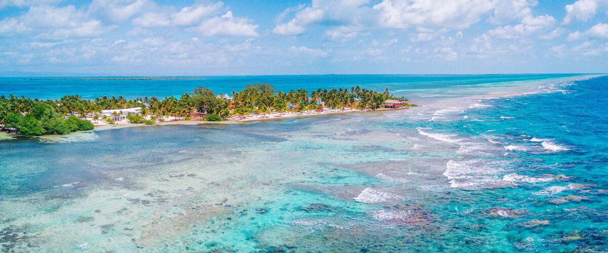 A tropical island with clear turquoise waters, a sandy beach, and lush greenery.