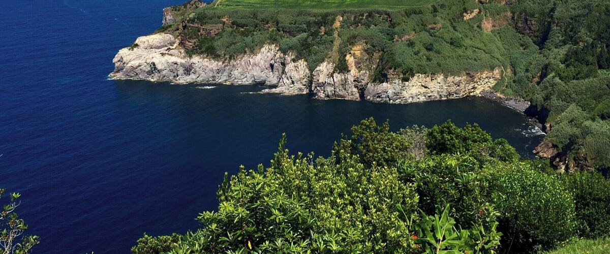 A coastal landscape with cliffs, a golf course, and a view of the ocean.