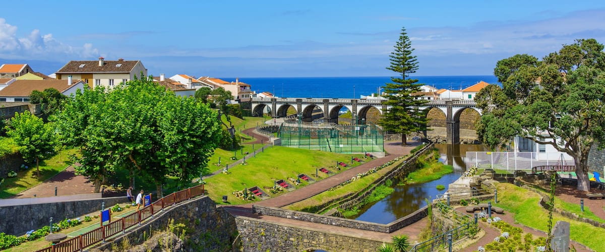 A coastal town with a bridge, a river, and lush greenery.