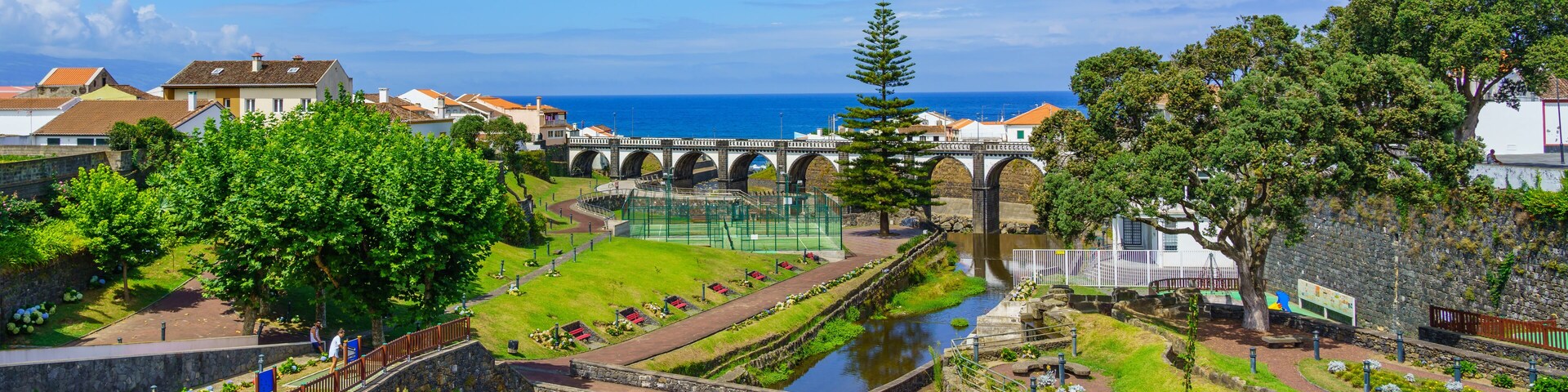 A coastal town with a bridge, a river, and lush greenery.