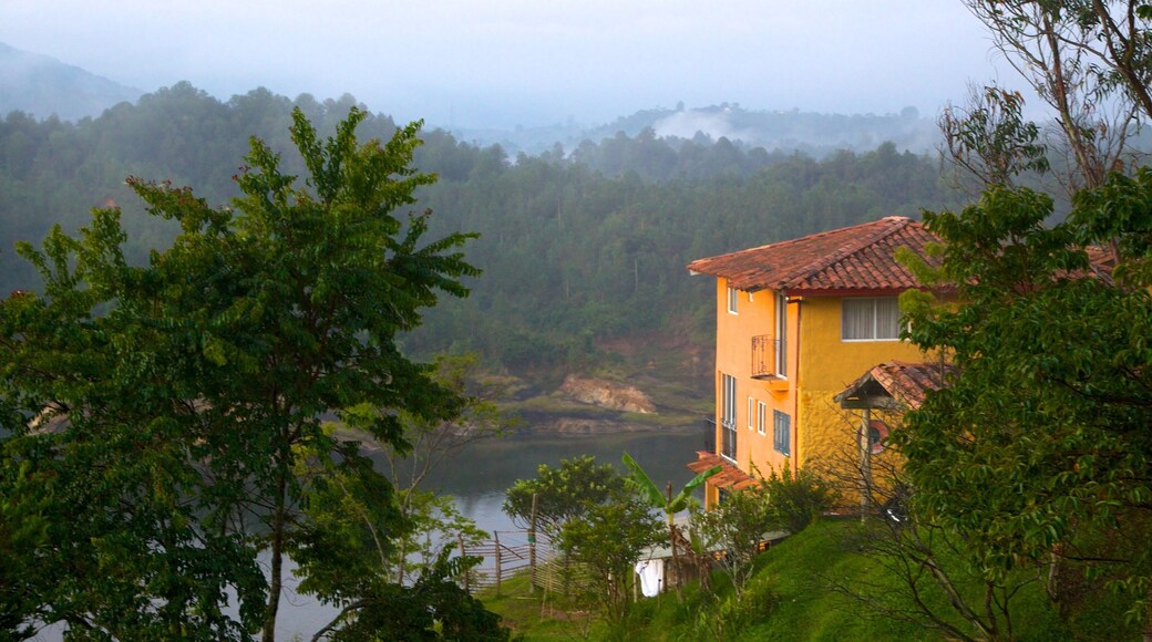 Rock of Guatape showing mist or fog, a house and a lake or waterhole