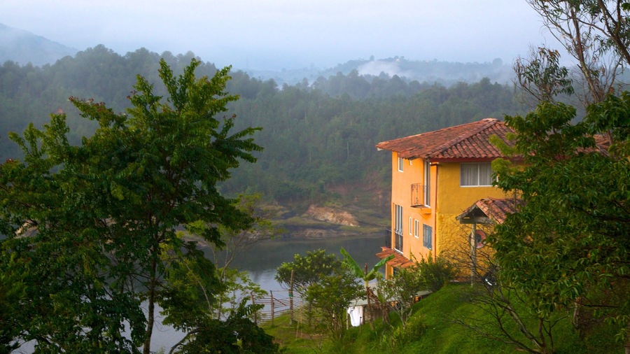Rock of Guatape which includes a lake or waterhole, a house and forest scenes
