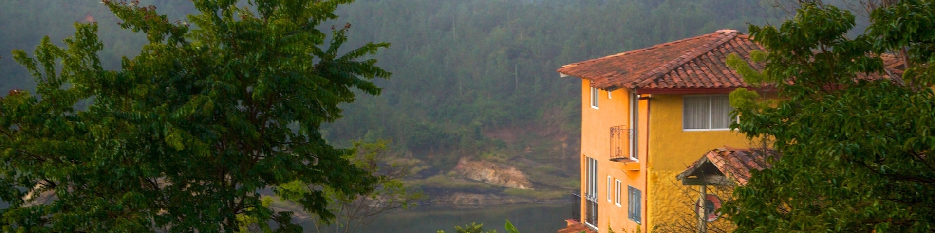 Rock of Guatape showing mist or fog, a house and a lake or waterhole