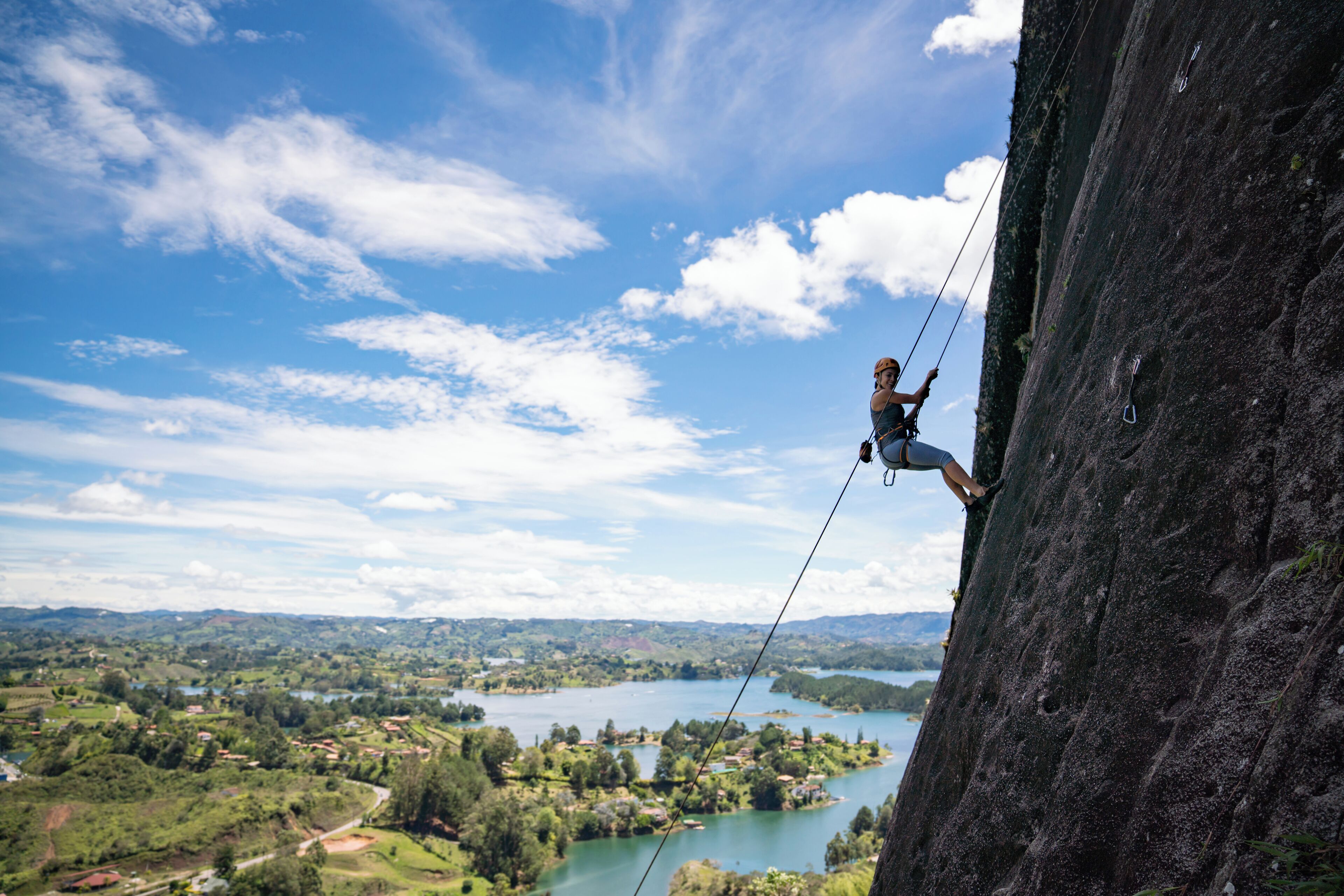 Strong woman rock climbing at Guatape and looking very happy - extreme sports concepts