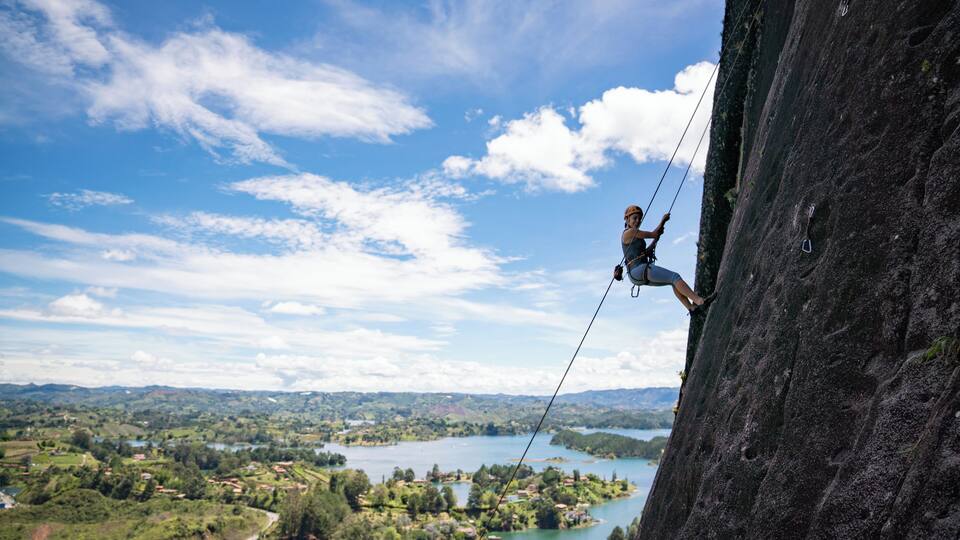 Strong woman rock climbing at Guatape and looking very happy - extreme sports concepts