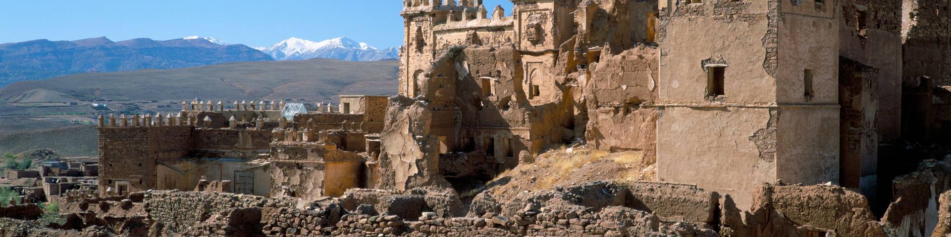 Ruins of Glaoui kasbah at Telouet, with snow capped High Atlas Mountains in distance, Telouet, Morocco