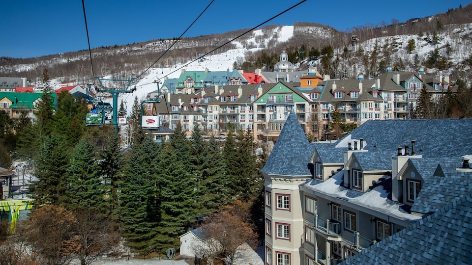 A snow-covered mountain with a ski resort and colorful buildings in the foreground.