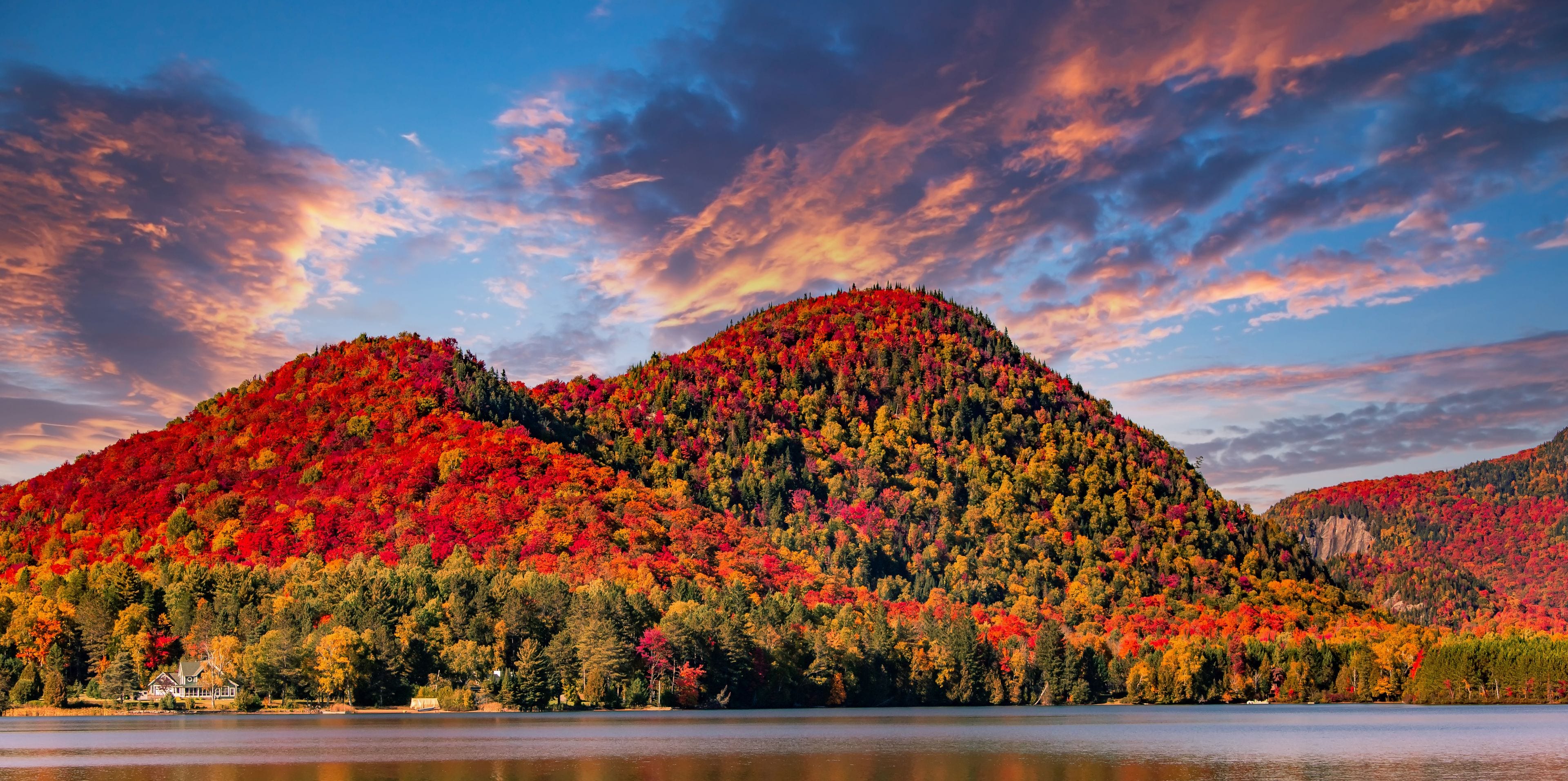A lake surrounded by autumn-colored hills with a house near the water.