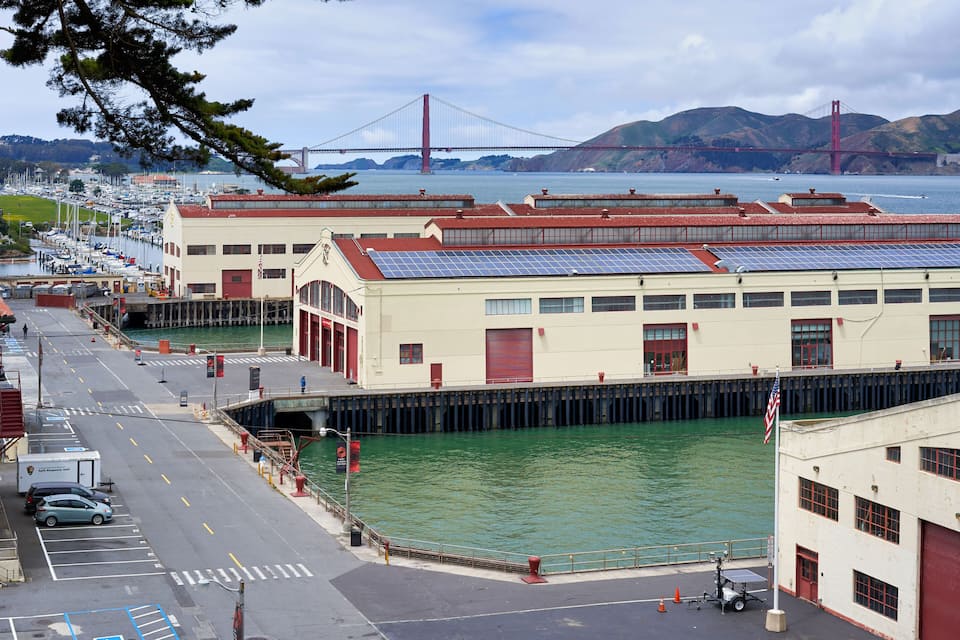 A harbor with a bridge in the background, a marina with boats, and a building with solar panels.